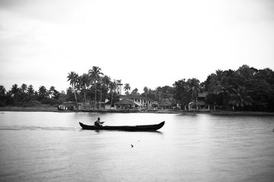 People in boat on lake against clear sky