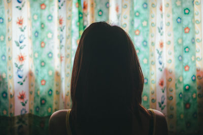 Rear view of woman standing against curtain