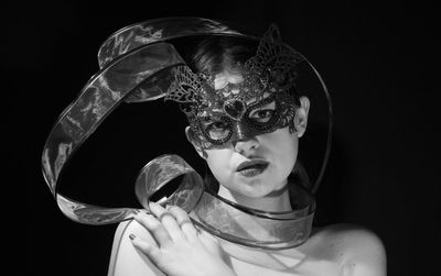 Portrait of woman wearing mask against black background