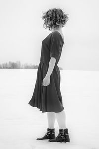 Rear view of woman standing on field against sky