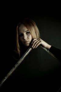 Portrait of a young woman over black background