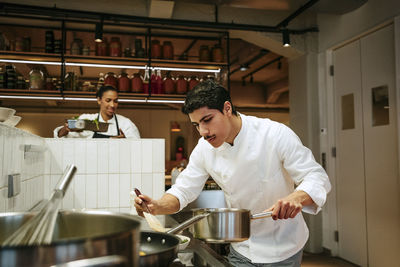 Male chef preparing food with spatula in commercial kitchen