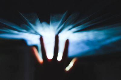 Close-up of cropped hand against illuminated light at night