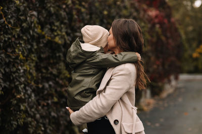 Happy mother and little son child walking in the autumn forest in nature in fall