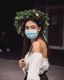 Close-up of young woman wearing mask standing outdoors