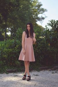 Portrait of young woman standing against trees