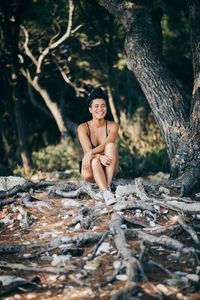 Young woman wearing bikini while sitting on field