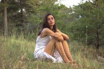 Portrait of young woman sitting on field