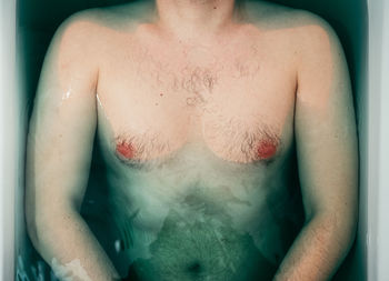 Midsection of shirtless man in bathtub