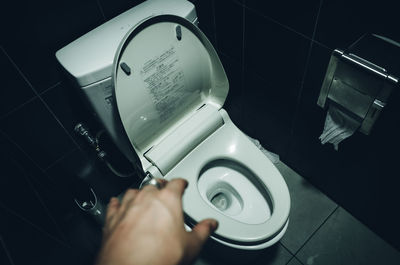 Cropped hand over toilet seat