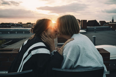 Affectionate woman kissing female partner while enjoying on building terrace