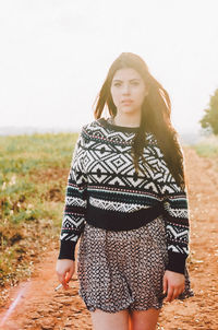 Portrait of woman standing on field against clear sky