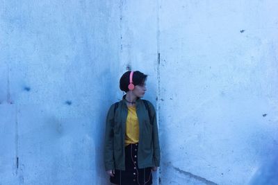 Full length of woman standing against blue wall