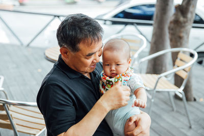 Grandfather holding grandson in porch