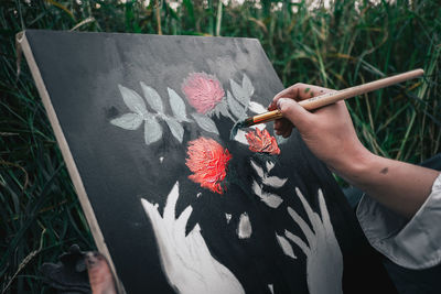 High angle view of person hand holding red flowering plant