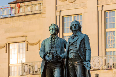 Statue of man standing against building