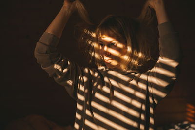 Portrait of woman standing against black background