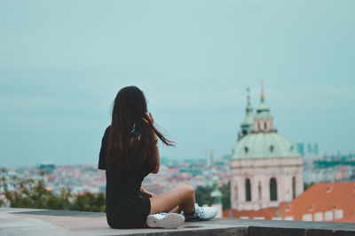 Woman with umbrella against sky in city