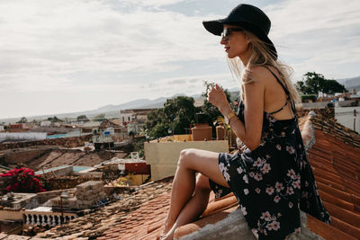 Side view of smiling woman sitting on rooftop