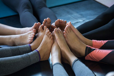 Low section of friends joining legs on floor