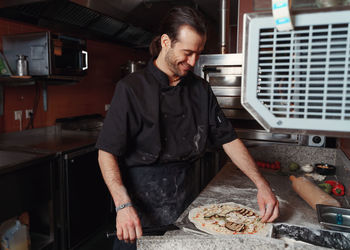 Pizza making process. male chef hands making authentic pizza in the pizzeria kitchen.