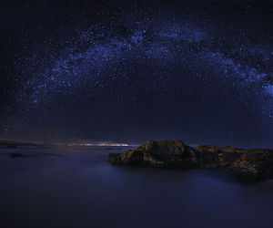 Scenic view of sea against star field at night