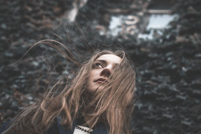 Low angle view of thoughtful woman standing against ivy