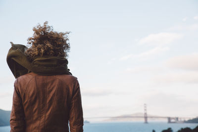 Rear view of woman looking at golden gate bridge against sky