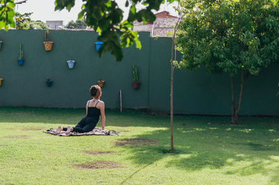 Rear view of woman exercising in back yard