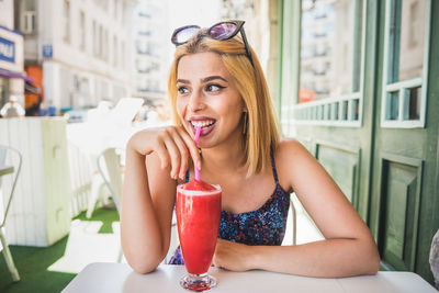 Portrait of a smiling young woman drinking glass