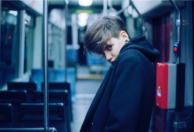 Side view portrait of young man standing in train