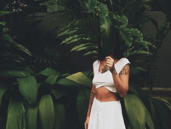 Woman covering face with leaf against plants