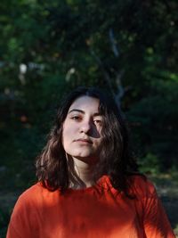 Portrait of beautiful young woman against trees