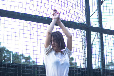 Woman with arms outstretched standing against built structure