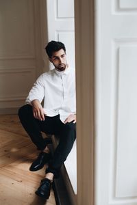 Young man sitting on window sill at home