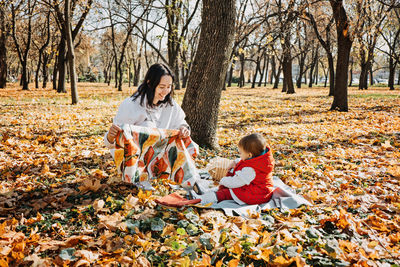 Happy family mother and little toddler baby daughter having fun together in autumn picnic