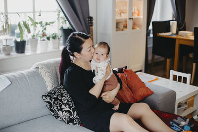 Woman sitting with baby on sofa