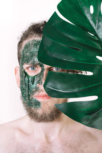 Portrait of shirtless man wearing glitter against leaf 