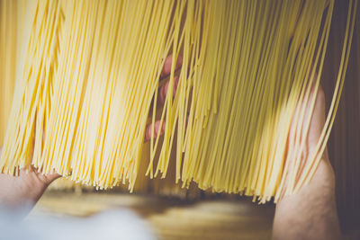 Cropped image of hand checking spaghetti drying in factory