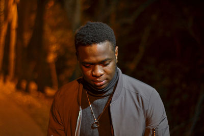 Thoughtful young man looking down while standing on road at night