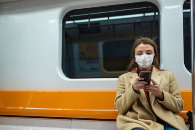 Portrait of man using mobile phone in train