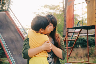 Mother kissing daughter while playing at playground