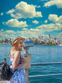 Woman by lake against sky in city