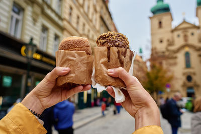 Woman holding two traditional chimney cakes at street of prague, czech republic