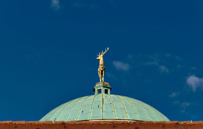 Low angle view of deer statue on dome against blue sky