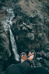 Low section of person sitting on rock