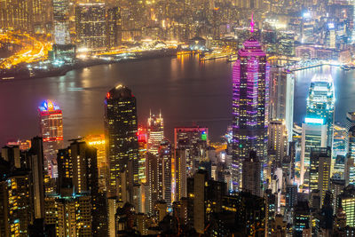 Illuminated buildings at victoria harbour in city during night