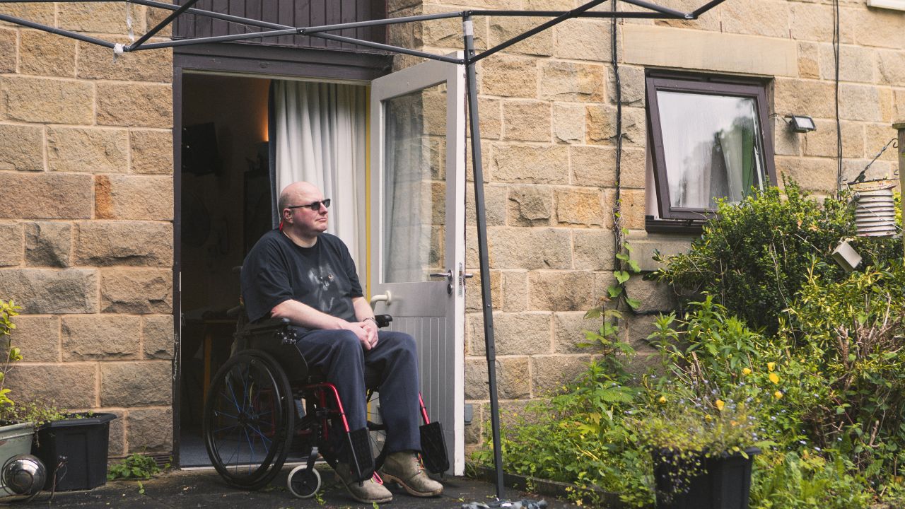 Person sat in a wheelchair at the door of their house looking out into their backyard