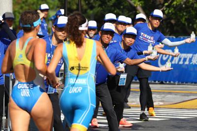 厳しい暑さの中、選手に水を手渡すスタッフ＝東京都港区で２０１９年８月１７日、佐々木順一撮影