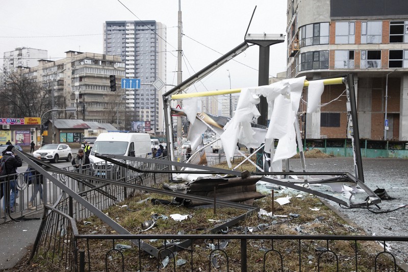 ウクライナの首都キエフで、ロシアの砲撃で破壊された建造物と、そのそばを歩く人々＝2022年2月24日、AP